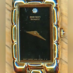 Seiko Ladies Black dial, 2 hand movement gold case and bracelet w/diamond at 12